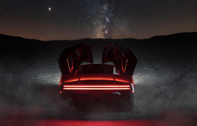 Tesla Roadster rear view with butterfly doors open under the Milky Way, red light bar glowing